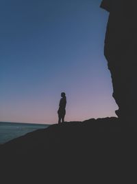 Silhouette woman standing on beach against clear sky during sunset