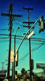 Low angle view of electricity pylon against blue sky