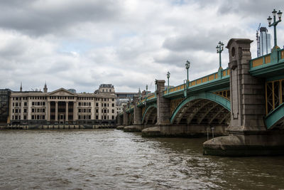 Bridge over river against buildings in city