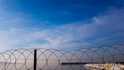 Low angle view of chainlink fence against sky