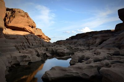 Rock formations by mountains against sky