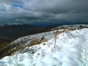 Scenic view of snowcapped mountains against cloudy sky