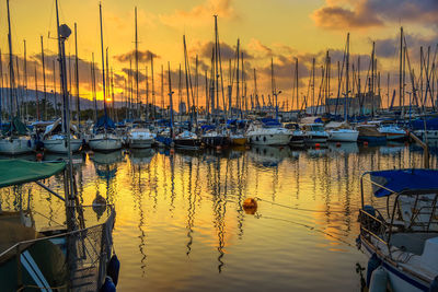 Boats moored in harbor during sunset