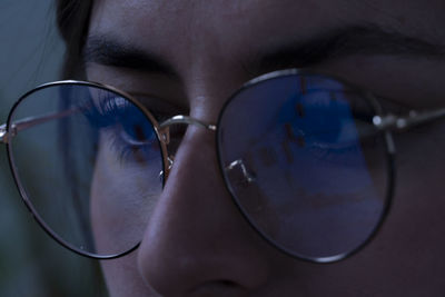 Young woman, watching the stock market at night, the same market  seen in reflection of her glasses