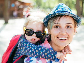 Portrait of smiling mother giving piggyback ride to daughter