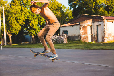 Full length of shirtless man skateboarding