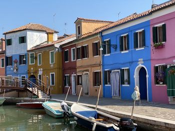 Boats moored in canal by buildings against sky