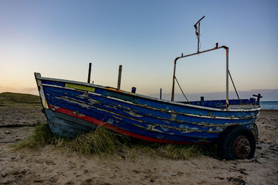 Boats moored on beach against clear sky