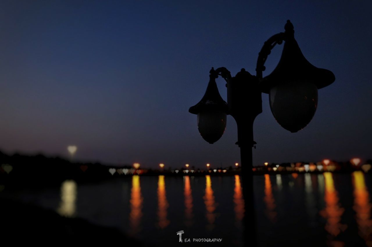 illuminated, water, night, reflection, waterfront, clear sky, copy space, sky, dusk, river, sea, lighting equipment, lake, tranquility, no people, outdoors, silhouette, light, blue, city