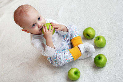High angle view of baby eating apple