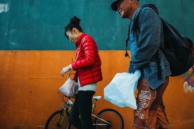 Side view of people riding bicycle against wall