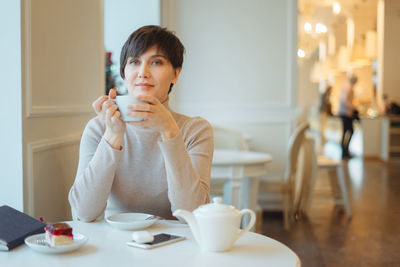 Portrait of woman holding coffee cup while siting at cafe