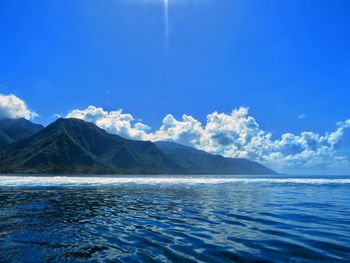 Scenic view of lake and mountains against blue sky