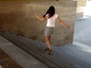 Rear view of young woman moving down on steps