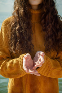 Midsection of woman wearing sweater outdoors