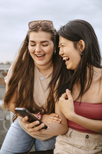 Young women laughing while sharing smart phone