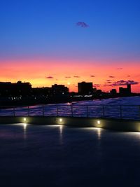 Swimming pool by sea against sky during sunset