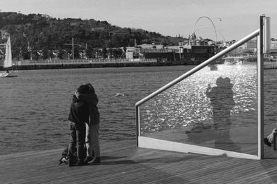 Rear view of people standing by railing against sky