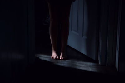 Low section of woman standing by door in room at home