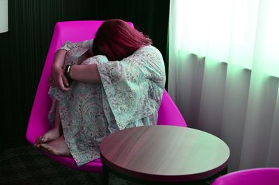 Side view of depressed woman sitting on chair at home
