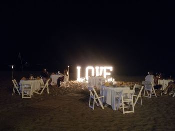 People relaxing on table at beach at night