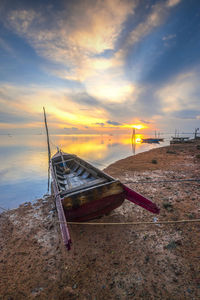 Sailboat moored on beach against sky during sunset