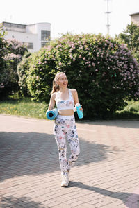 Athletic happy healthy young woman in sportswear goes after a sports workout exercise in nature