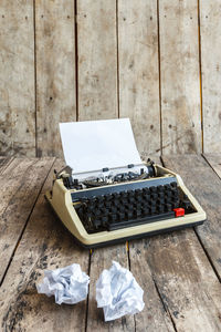 High angle view of typewriter with crumpled papers on wooden table