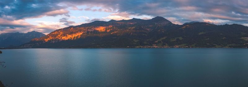 Scenic view of lake by mountains against sky during sunset