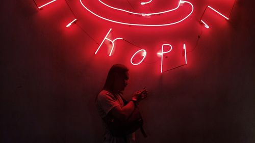 Full length of woman standing against illuminated wall