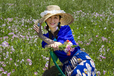 Portrait of a smiling young woman with flower petals on field