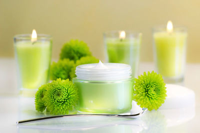 Close-up of beauty product with green flowers and candles