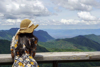 Rear view of woman looking at view of mountain range against sky