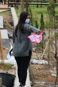 Rear view of woman with pink umbrella standing against plants