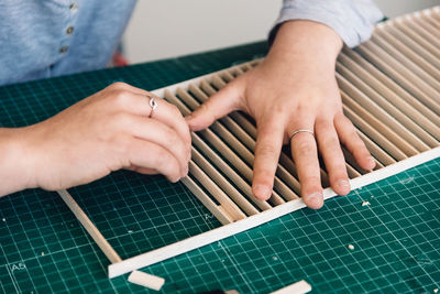 Cropped hands of woman making wooden decor on table