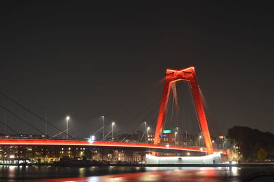 Illuminated bridge over river against sky at night