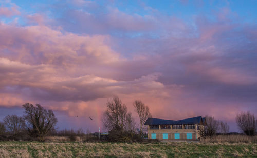 House on field against sky during sunset