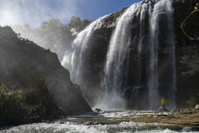 Man standing against waterfall