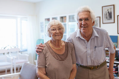 Portrait of senior couple standing arm around in nursing home