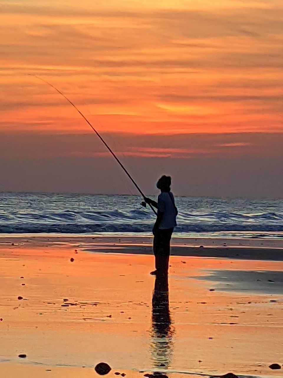 water, sea, fishing, sunset, sky, beach, land, one person, shore, nature, beauty in nature, activity, rod, fishing rod, ocean, horizon, orange color, men, leisure activity, silhouette, horizon over water, coast, standing, sports, full length, lifestyles, casting, motion, scenics - nature, holiday, vacation, sun, fisherman, adult, trip, cloud, wave, dusk, idyllic, sand, holding, reflection, body of water, outdoors, tranquility, occupation, travel destinations, tranquil scene, weekend activities, summer, recreation, angling, person