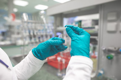 Cropped hand of scientist holding vial in laboratory