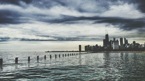 City at waterfront against cloudy sky