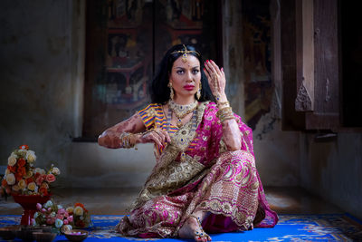 Full length of woman wearing sari and jewelry while sitting at home