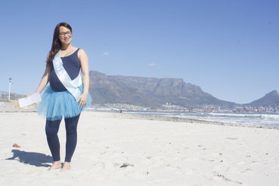 Portrait of smiling pregnant woman wearing sash at beach