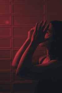 Portrait of woman against red wall