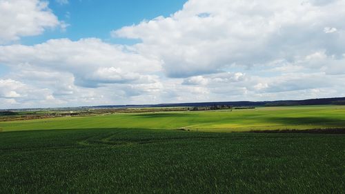 Scenic view of grassy field against cloudy sky