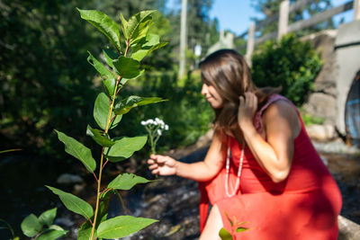 Young woman standing against plants