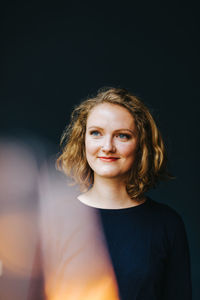 Portrait of smiling young woman against black background