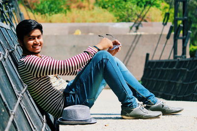 Smiling young woman using mobile phone in park