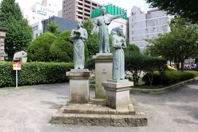 Statue in park against buildings in city